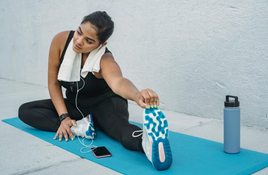 Woman Sitting on a Yoga Mat and Stretching