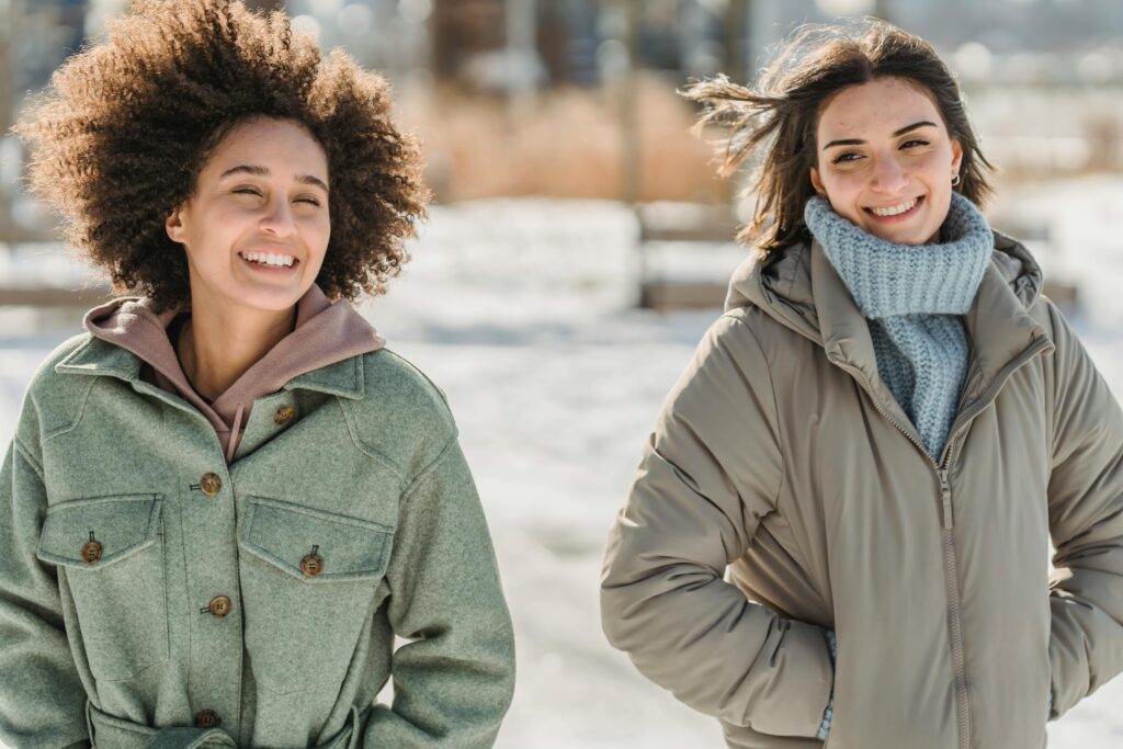 Positive multiethnic girlfriends walking on snowy street