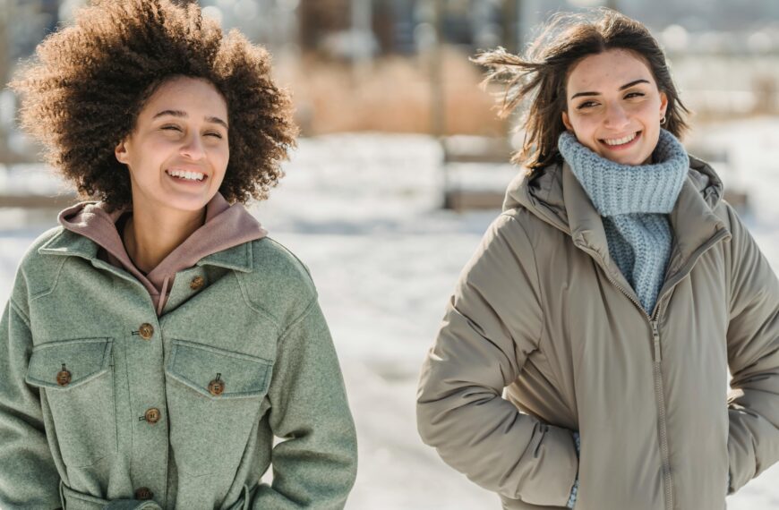 Positive multiethnic girlfriends walking on snowy street